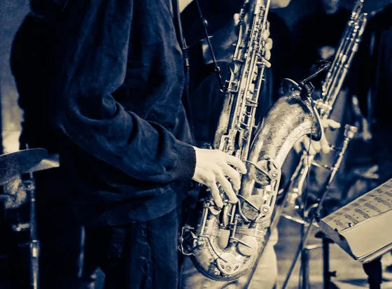 Close-up of a saxophone section mid-performance, instruments and hands in cool blue light